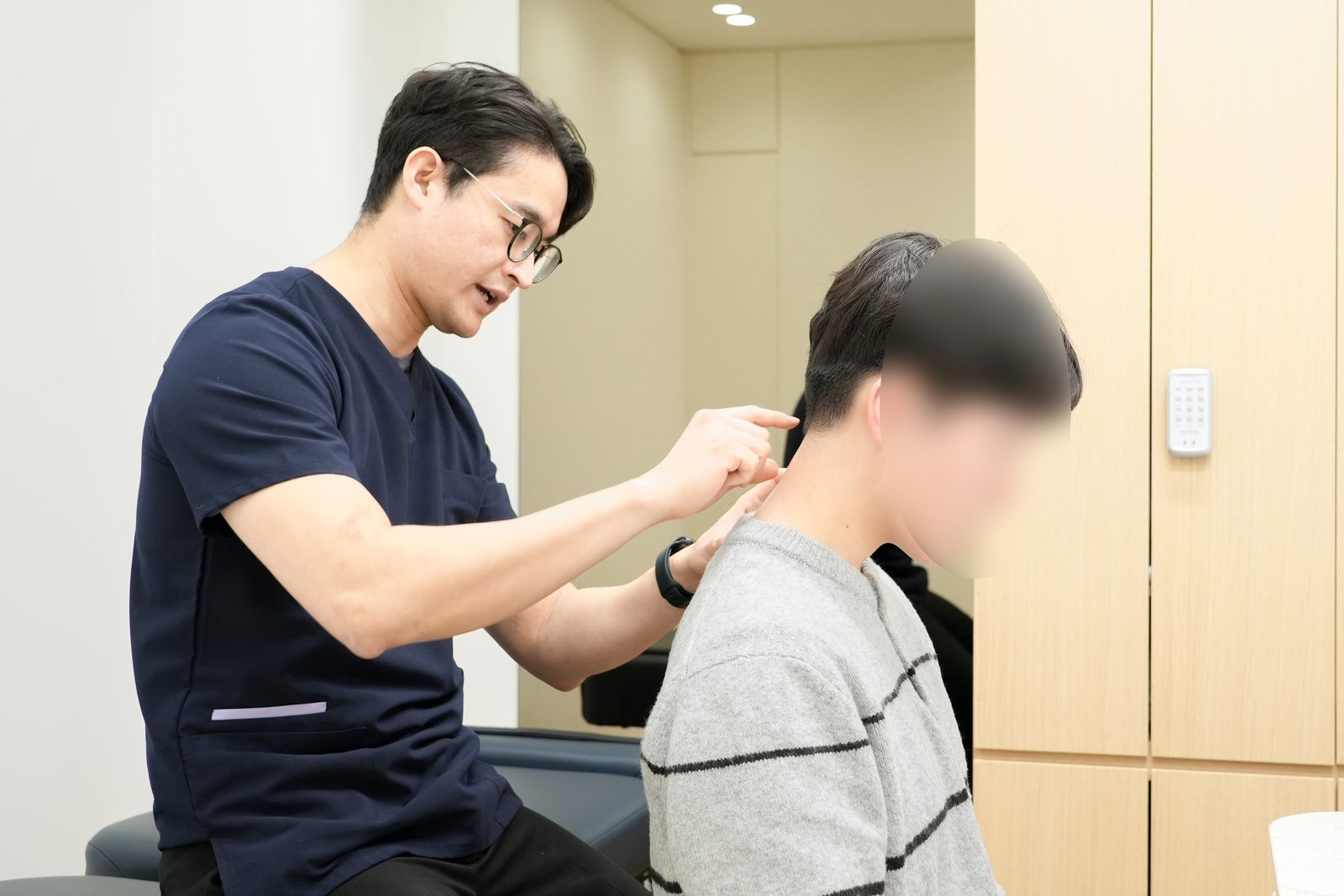 오종석 대표원장이 앉아 있는 환자의 목뼈 마디를 손끝으로 지지하며 멀리건 추나를 적용하는 장면 - 마포당한의원 마포 추나
